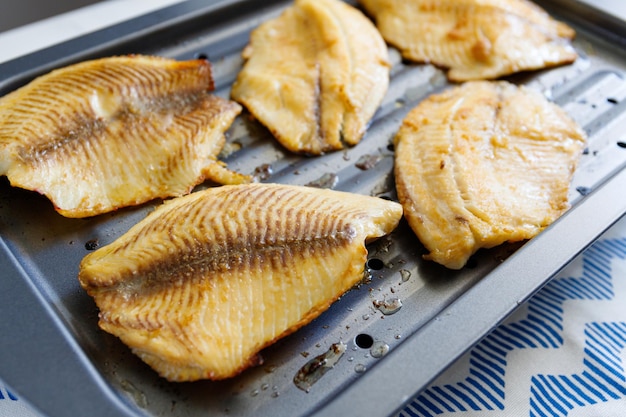 Closeup of tilapia fillets on a broiling pan Recipe for healthy home dinner or lunch