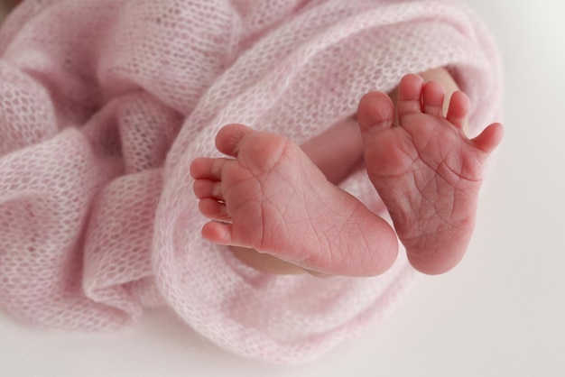 Closeup of tiny cute bare toes heels and feet of a newborn girl boy Baby foot on pink soft coverlet blanket Detail of a newborn baby legs Macro horizontal professional studio photo