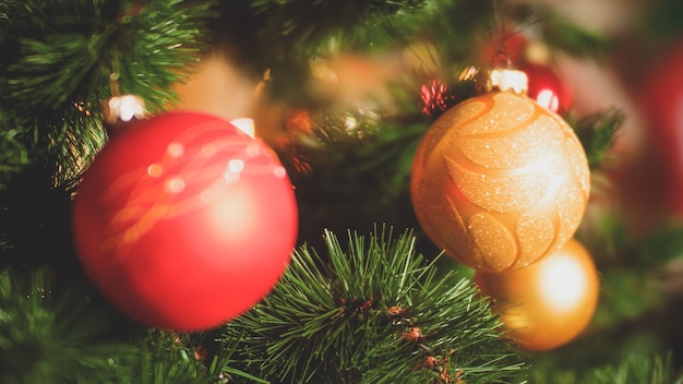 Closeup toned photo of needles and colorful baubles on Christmas tree. Perfect background for winter holidays and celebrations