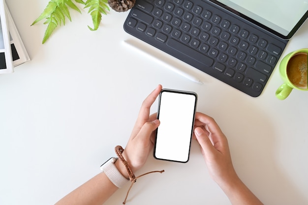 Closeup and top view of female using mobile smartphone on office white desk