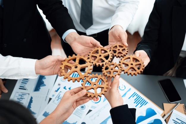 Closeup top view hands holding gears over table with BI reports for harmony