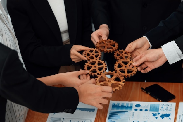 Closeup top view hands holding gears over table with BI reports for harmony