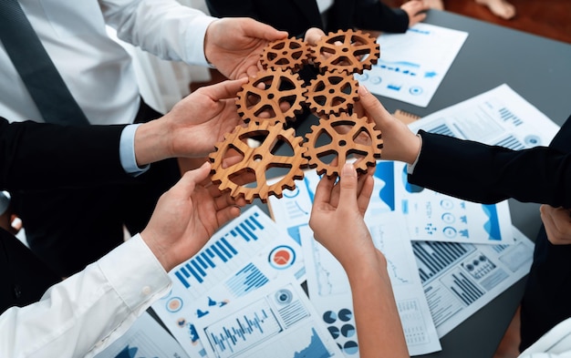 Closeup top view hands holding gears over table with BI reports for harmony