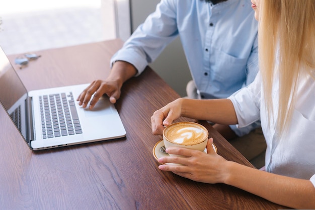 Closeup top view hands of unrecognizable business man and woman working with laptop sitting at table