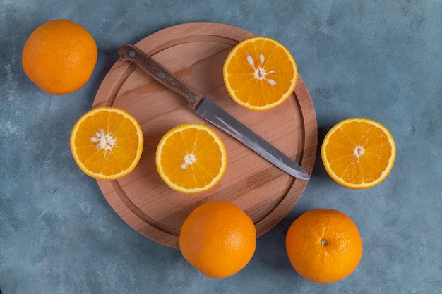 Closeup top view of ripe whole and halved oranges on round cutting board