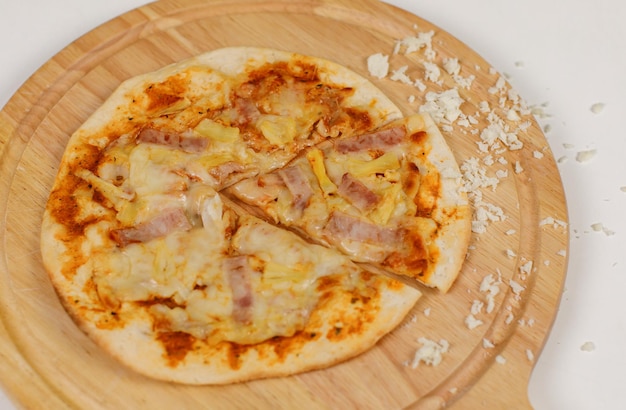 Closeup top view studio shot of tasty delicious Italian homemade mozzarella cheesy ham pineapple original Hawaiian pizza soft bread crust on wodden plate served on table in restaurant