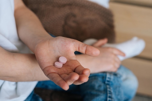 Closeup top view of unrecognizable little girl holding medical pills in hands