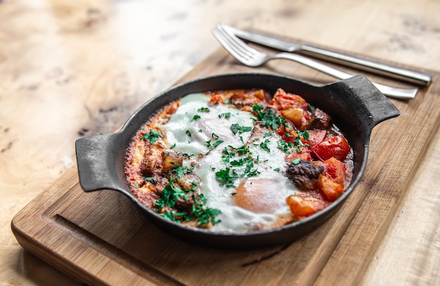 Closeup of traditional shakshuka in a frying pan on a wooden background