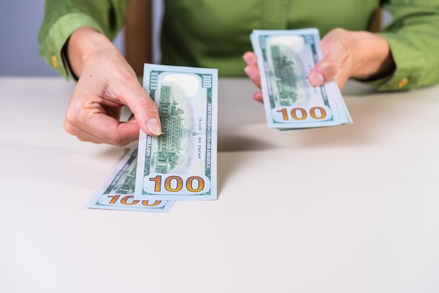 Closeup of two caucasian female hands holding many dollars. Hundred dollars, cash flow.