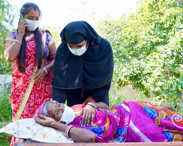 Closeup of two females calling for an ambulance for an old sick woman