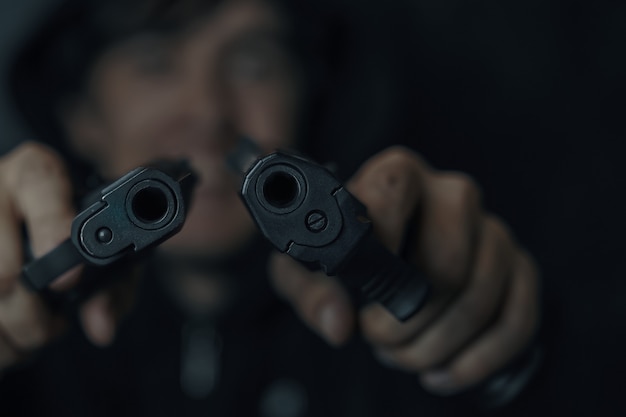 Closeup of two gun muzzles man threatens with firearm criminal with weapon two pistols in mans hands...