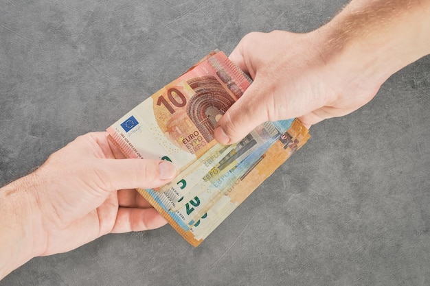 Closeup of two hands of people exchanging euro banknotes of different denominations for buying and selling paying or taxing a debt borrowing funds Top view high quality photo money loan