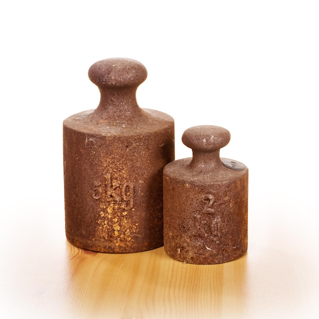 Closeup of two old rusty weights with five and two kilograms on wooden floor