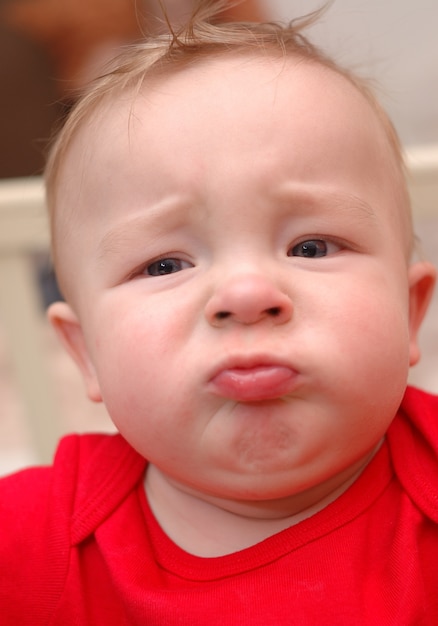 Closeup of unhappy caucasian boy in red t-shirt.