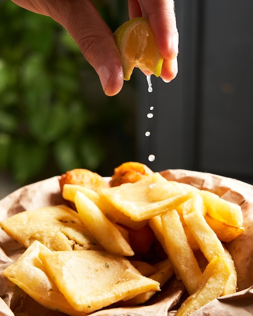 Closeup of unrecognizable man squeezing a lemon smoothly over french fries