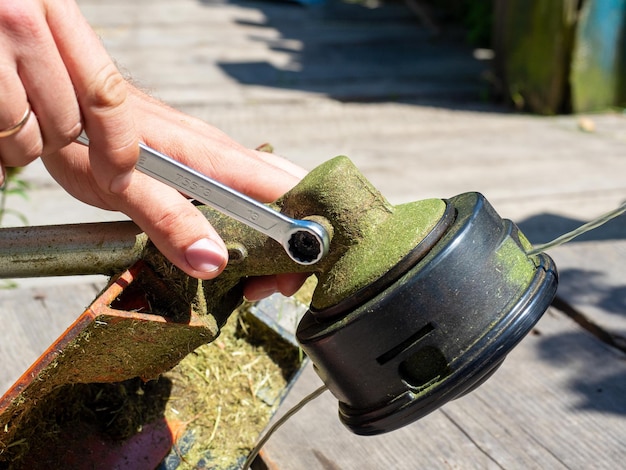 Closeup of unscrewing the screw on the gearbox of a gasoline trimmer with a wrench Maintenance of equipment