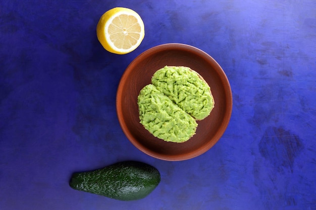 Closeup vegetarian breakfast toasts with avocado smash on a clay plate Toasts and green avocado and yellow lemon on a blue background View from above