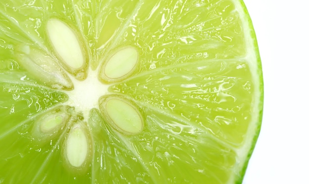 Photo closeup of vibrant green lime cut in half with seeds on white background