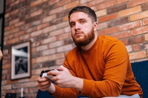 Closeup view of bearded handsome bearded young man holding controllers and playing video games on console