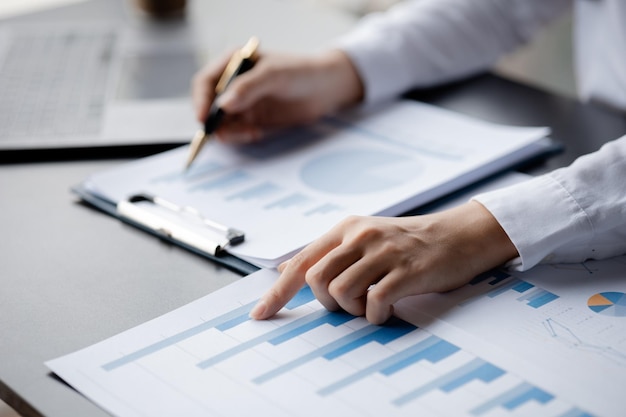 A closeup view of a businessman pointing at a bar chart on a company financial document prepared by the Finance Department for a meeting with business partners Financial concept