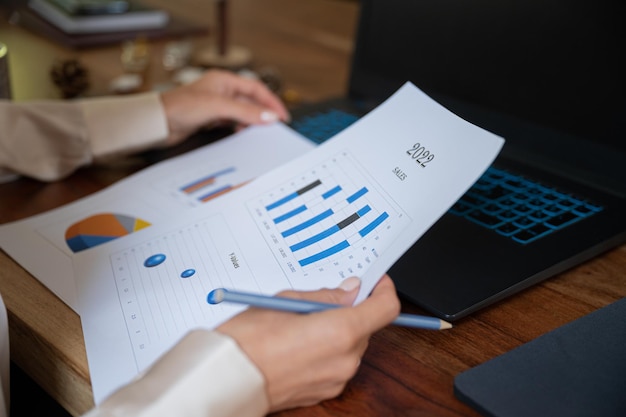 Closeup view of businesswoman reviewing sales plan with graphic statistics for the year of 2022 in a conceptual business image.