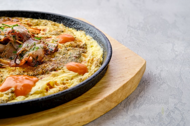 Closeup view of eggs with bell pepper and tomato baked in oven in cast-iron skillet