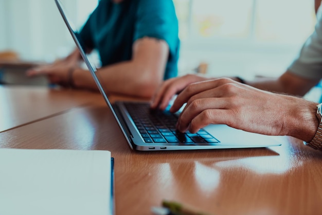 In a closeup view the fingers of a man are seen typing swiftly on a laptop keyboard depicting a