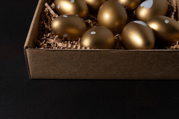 Closeup view of Gold eggs in paper box on black background