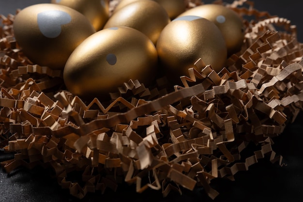 Closeup view of Gold eggs in paper nest on black background