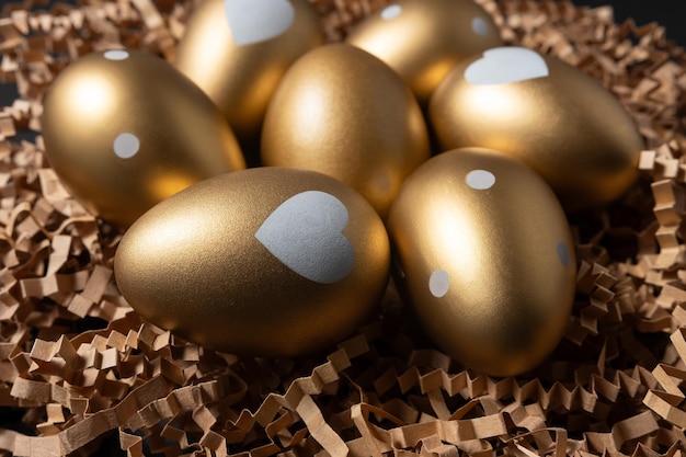 Closeup view of Golden eggs in paper nest on a dark table