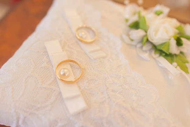 Closeup view of golden wedding rings on decorative white lace pillow