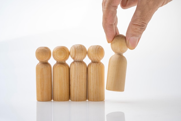 Closeup view of a human hand picking up one of a row of wooden figures