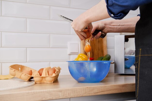 Closeup view of a man breaks an egg to a bowl to make an omelet