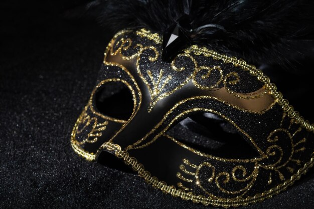 Closeup view of Masquerade gold mask with feathers on black background