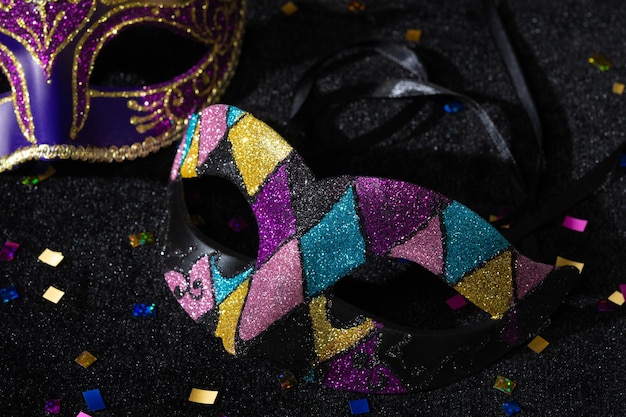 Closeup view of Masquerade mask with confetties on black background