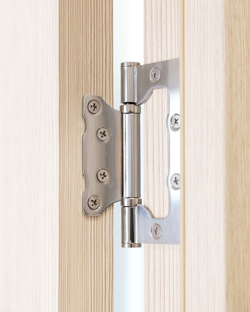 Closeup view of metal door hinge with wooden door