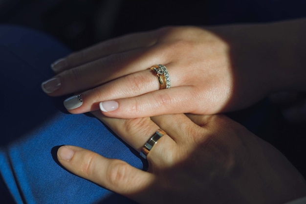 Closeup view of newlyweds hands holding colorful wedding bouquet bride and groom wearing wedding rin