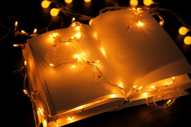 Closeup view of open books and beautiful garland on table