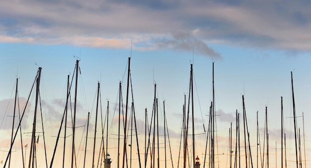 Closeup view of row of sailboat masts in a harbor under a colorful cloudy sky