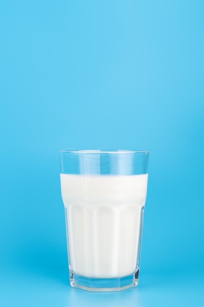 Closeup view of white milk in transparent faceted glass on blue background side view Dairy product