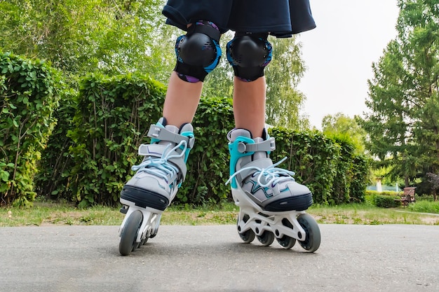 Closeup view of white roller skates or rollerblading. Roller skate legs of a child in the park. Girl legs in roller blades.