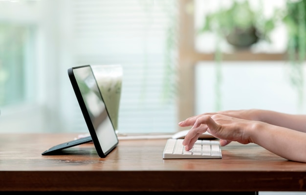 Closeup view of woman hands typing on computer keyboard while working from home.