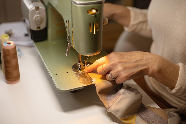 Closeup view of womans hands sewing fabric with a vintage, retro sewing machine. Fashion, creation and tailoring. Process of sewing in atelier or workshop.