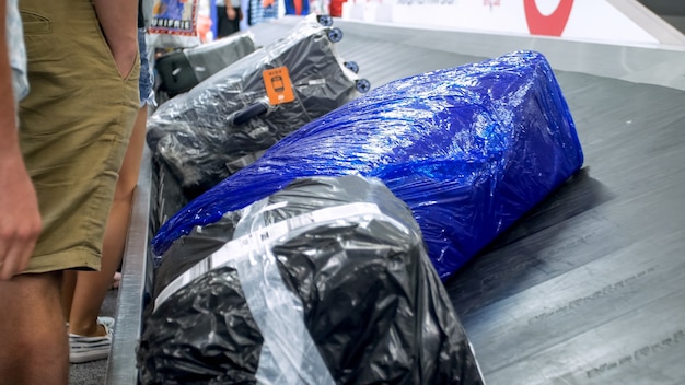 Closeup view of wrapped suitcases lying on the luggage claim line at airport.