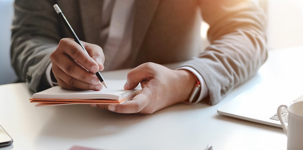 Closeup view of young professional businessman writing his idea concepts on notebook