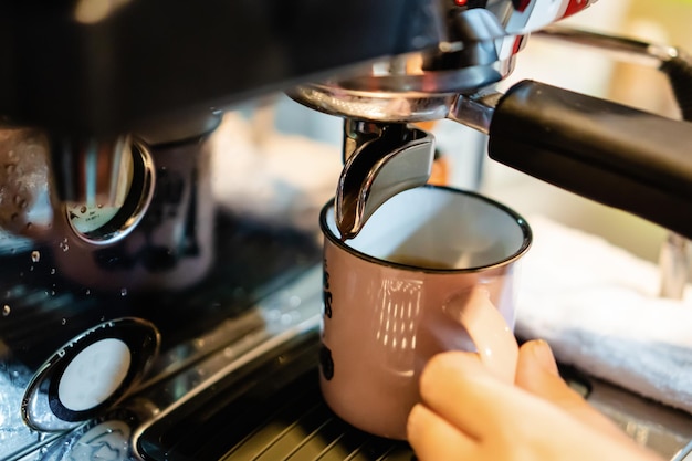 Closeup of a vintage mug in an espresso machine with hot coffee coming out of the spout