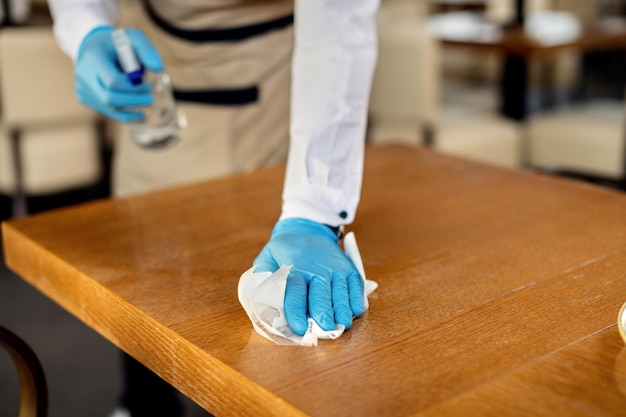 Closeup of waiter disinfecting table in a cafe