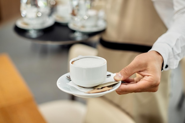 Closeup of a waiter serving coffee in a cafe