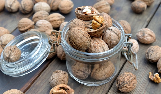 Closeup on walnuts in a glass jar among others on wooden table