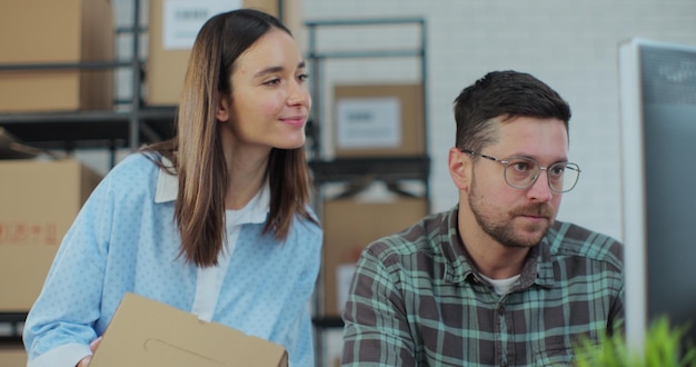 Closeup of a warehouse manager and an employee using a computer to talk about parcel delivery Business owners working in a warehouse prepare online orders for customers